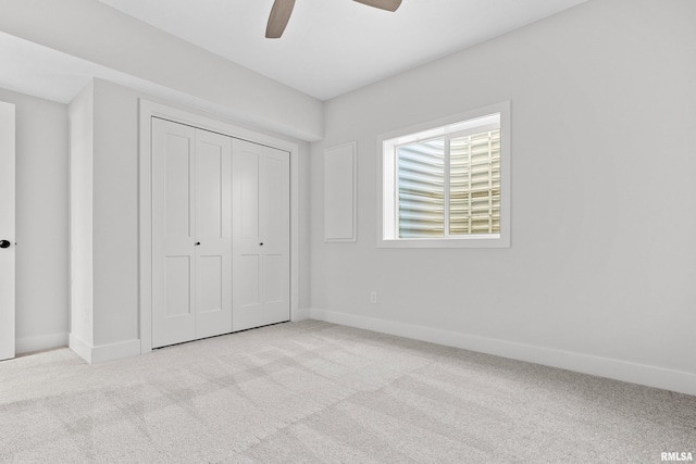 unfurnished bedroom with a closet, light colored carpet, and ceiling fan