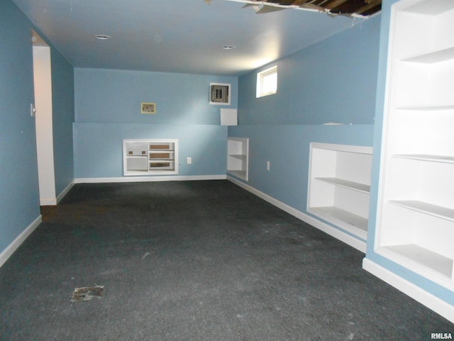 unfurnished room with dark colored carpet, vaulted ceiling, and built in features