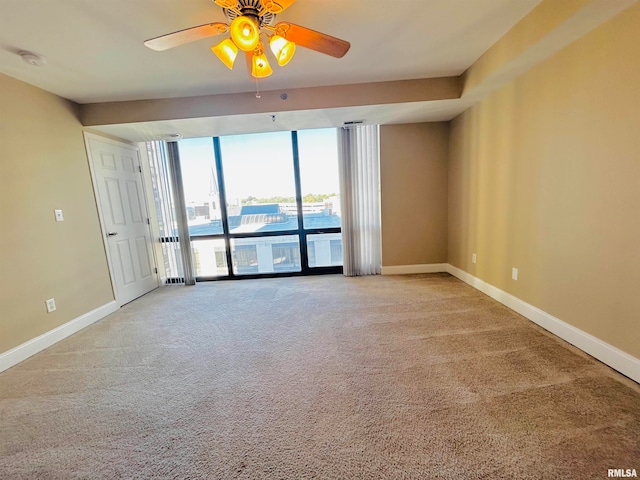 carpeted empty room featuring a wall of windows and ceiling fan