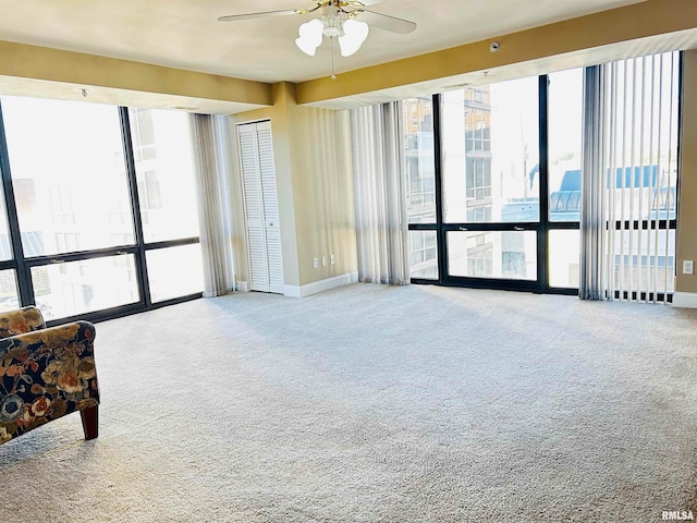 carpeted empty room with ceiling fan and a healthy amount of sunlight