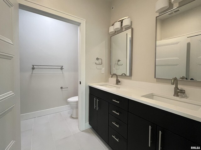 bathroom featuring toilet, dual bowl vanity, and tile patterned floors