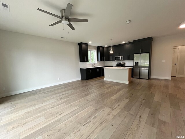 kitchen with ceiling fan, appliances with stainless steel finishes, a center island, and light hardwood / wood-style floors