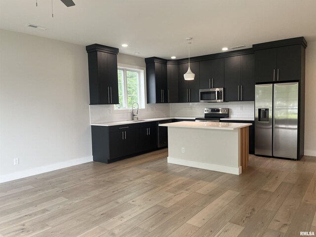 kitchen featuring stainless steel appliances, light hardwood / wood-style flooring, pendant lighting, and a kitchen island