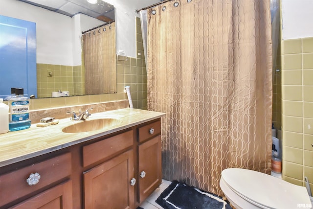 bathroom featuring a shower with shower curtain, vanity, toilet, and tile walls