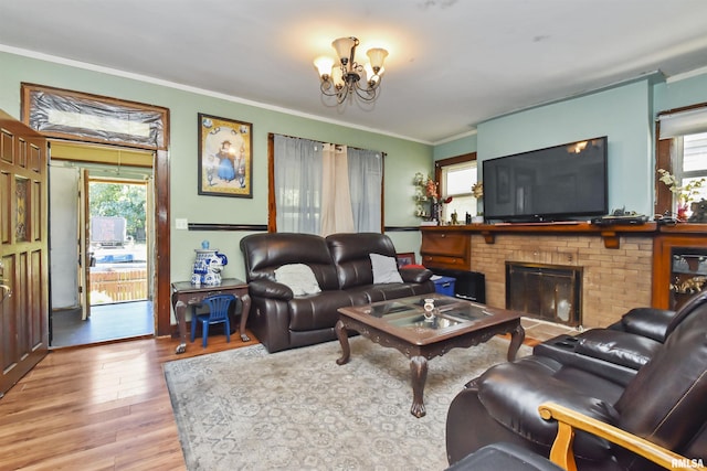 living room with hardwood / wood-style flooring, crown molding, a fireplace, and an inviting chandelier