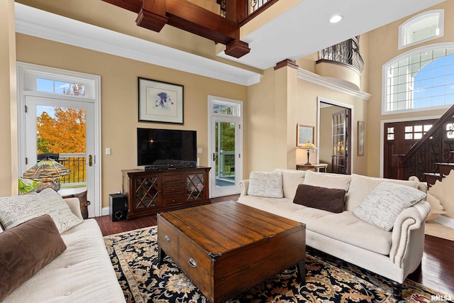 living room featuring stairway, ornamental molding, a healthy amount of sunlight, and wood finished floors