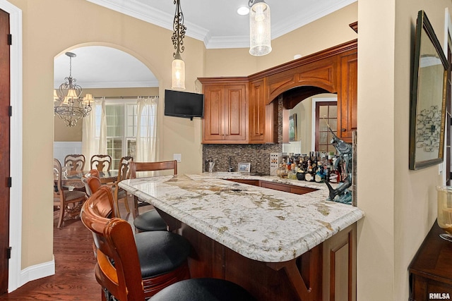 kitchen featuring a kitchen bar, arched walkways, a chandelier, and ornamental molding