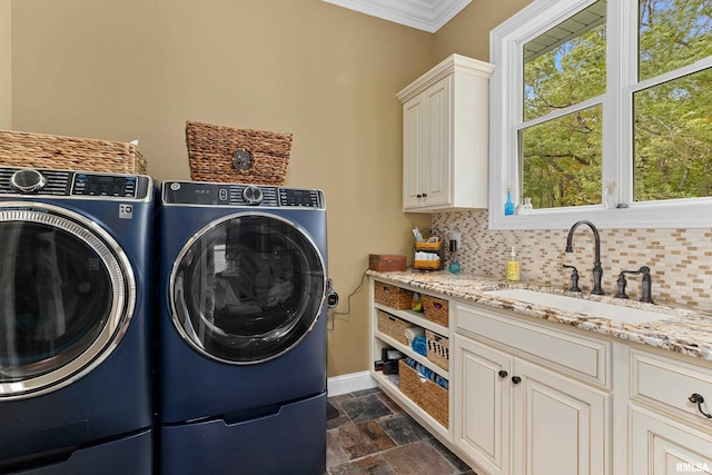 laundry room featuring stone tile flooring, a sink, washing machine and dryer, baseboards, and cabinet space