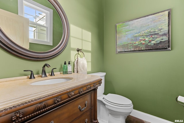 bathroom featuring baseboards, vanity, and toilet