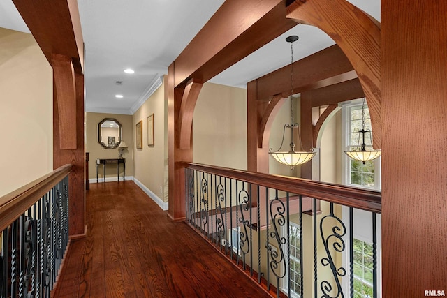hall with wood finished floors, a wealth of natural light, baseboards, and ornamental molding