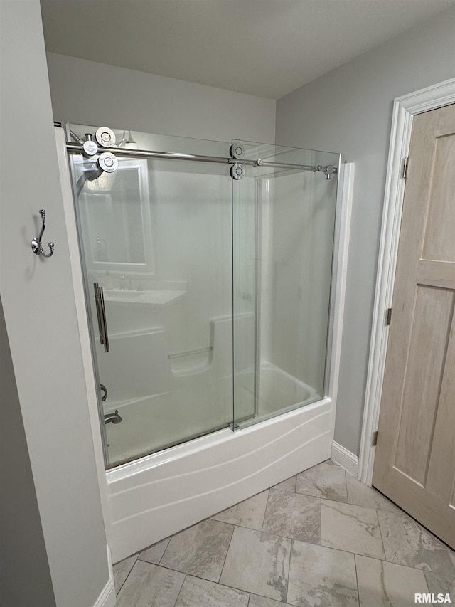 bathroom featuring baseboards, marble finish floor, and enclosed tub / shower combo