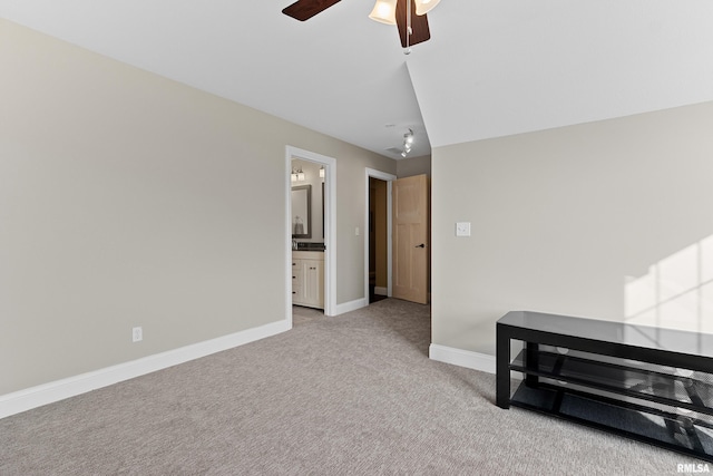 interior space with a ceiling fan, baseboards, and light carpet