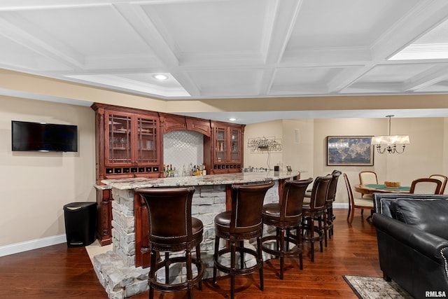 bar featuring baseboards, dark wood-style floors, coffered ceiling, and wet bar