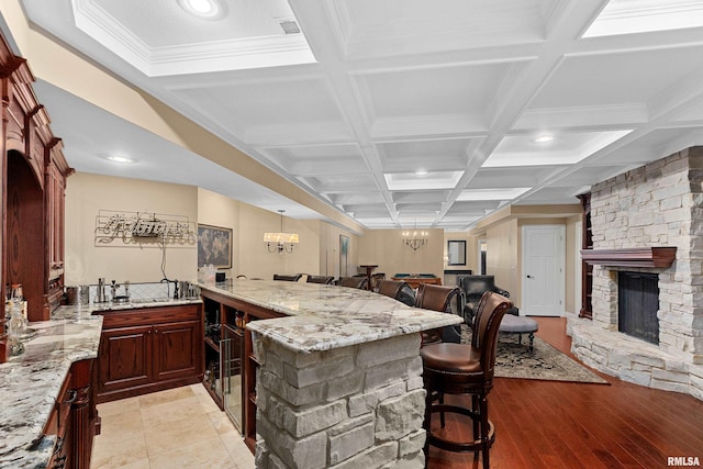 kitchen featuring open floor plan, light stone counters, and coffered ceiling