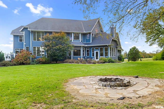 back of house featuring a fire pit, a chimney, and a yard