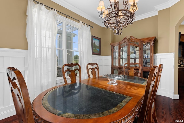dining space featuring wainscoting, an inviting chandelier, arched walkways, and a decorative wall