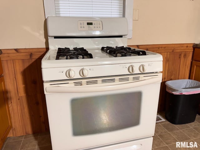 kitchen with dark tile patterned floors and white gas stove