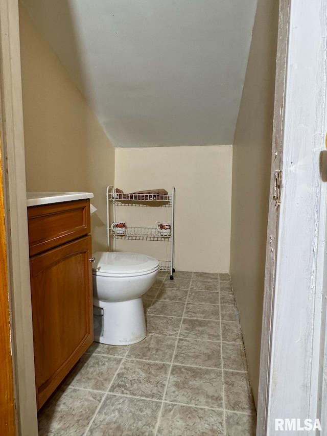 bathroom featuring vanity, toilet, and vaulted ceiling