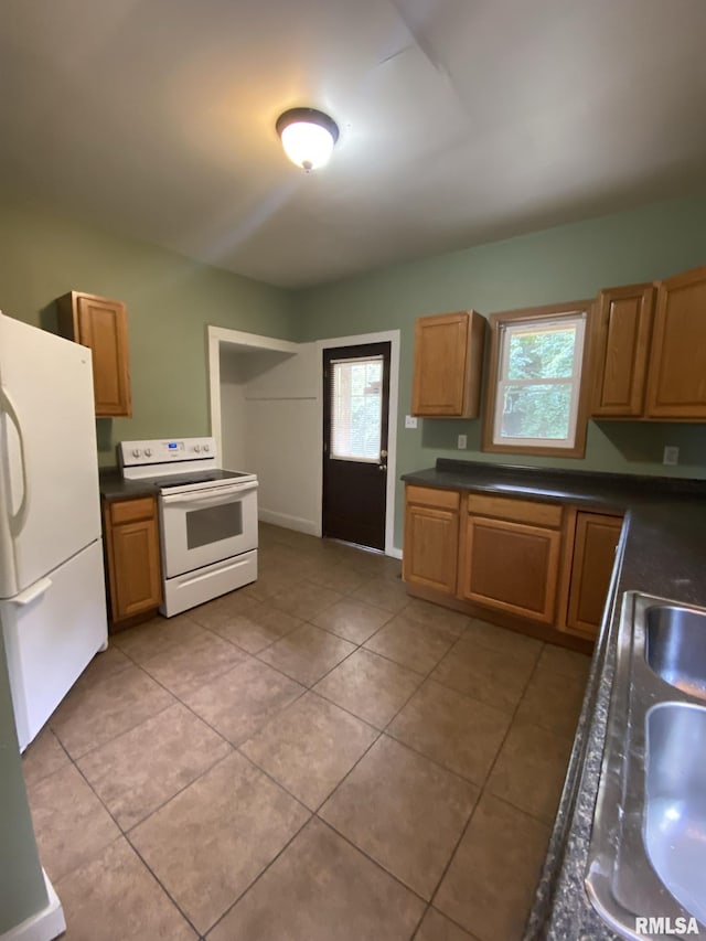 kitchen with light tile patterned floors, white appliances, and sink