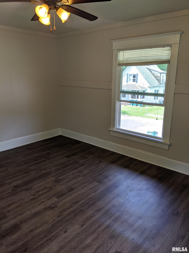 empty room featuring dark wood-type flooring, ceiling fan, and ornamental molding