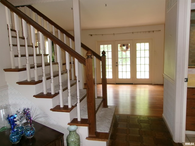 stairway with french doors and hardwood / wood-style floors