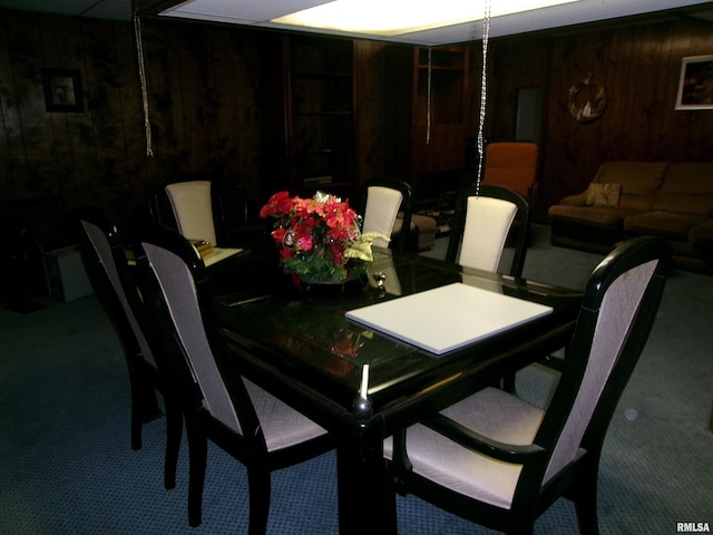 dining space with carpet flooring and wooden walls