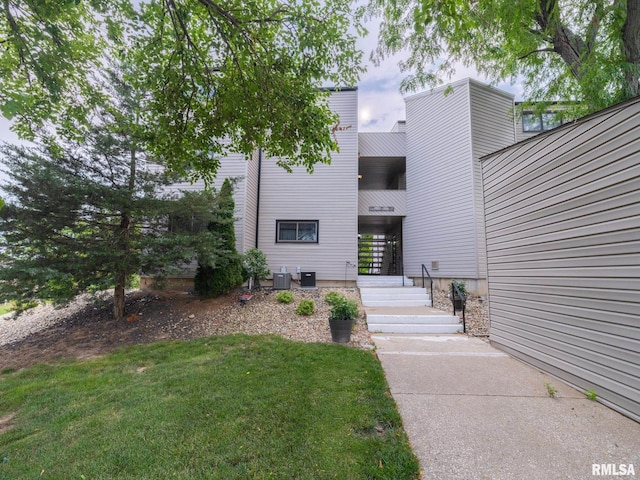 view of exterior entry with central AC unit and a lawn