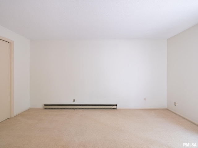 empty room featuring a baseboard heating unit and light colored carpet