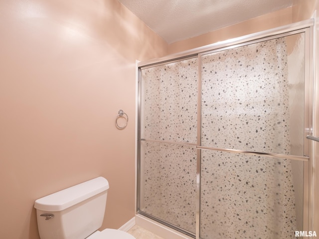 bathroom with a stall shower, a textured ceiling, and toilet