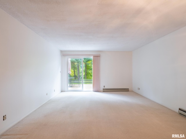 spare room featuring a baseboard heating unit, light colored carpet, and a textured ceiling