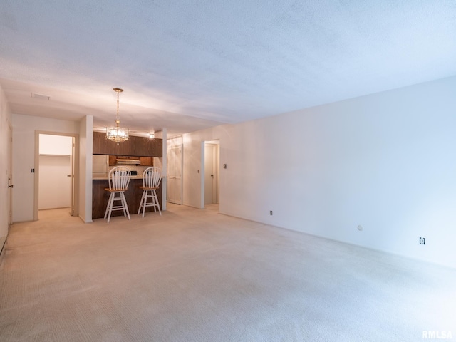 unfurnished living room with light carpet, a chandelier, and a textured ceiling