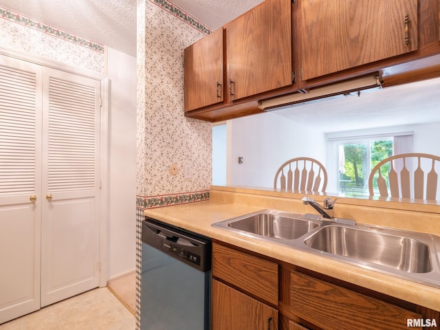 kitchen with dishwasher, brown cabinets, light countertops, a textured ceiling, and a sink