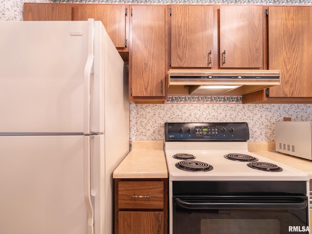 kitchen featuring electric range, decorative backsplash, freestanding refrigerator, light countertops, and under cabinet range hood