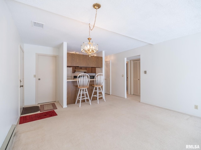 kitchen featuring visible vents, brown cabinetry, freestanding refrigerator, carpet, and baseboard heating