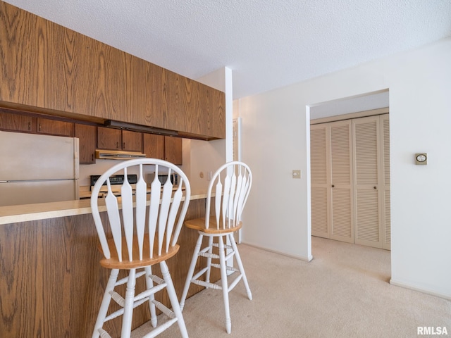 dining space with a textured ceiling and light colored carpet