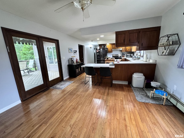 kitchen with baseboards, a peninsula, light wood-style flooring, light countertops, and black refrigerator with ice dispenser