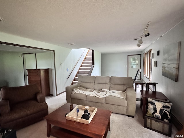 living room with light colored carpet, rail lighting, a textured ceiling, and stairs