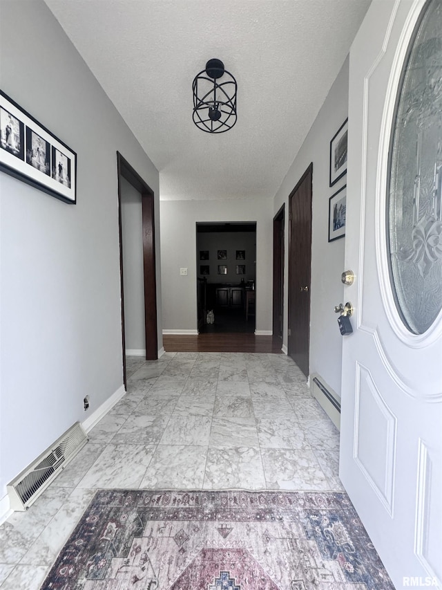 foyer with baseboards, visible vents, a baseboard radiator, a textured ceiling, and marble finish floor