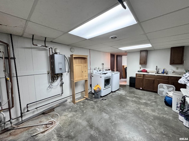 finished below grade area featuring visible vents, water heater, a drop ceiling, a sink, and independent washer and dryer