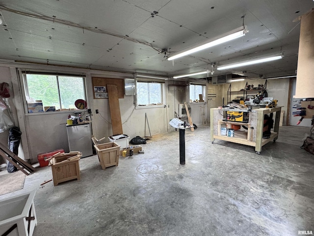 below grade area featuring plenty of natural light, a workshop area, and freestanding refrigerator