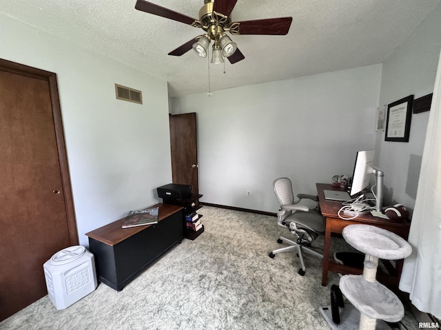 carpeted home office with ceiling fan, baseboards, visible vents, and a textured ceiling