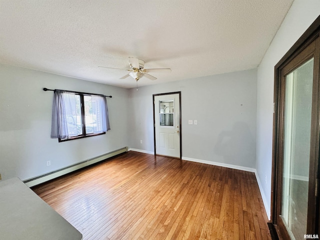 unfurnished room with a baseboard radiator, baseboards, a textured ceiling, and hardwood / wood-style flooring