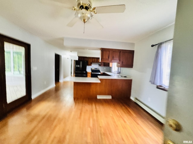 kitchen with a peninsula, light wood-style floors, freestanding refrigerator, and a baseboard radiator