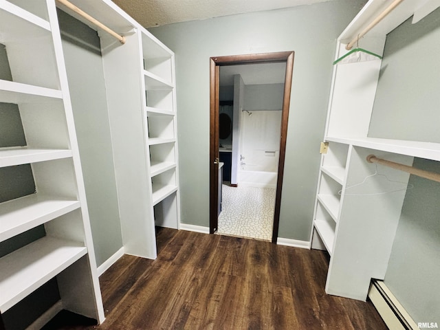 spacious closet with a baseboard heating unit and wood finished floors