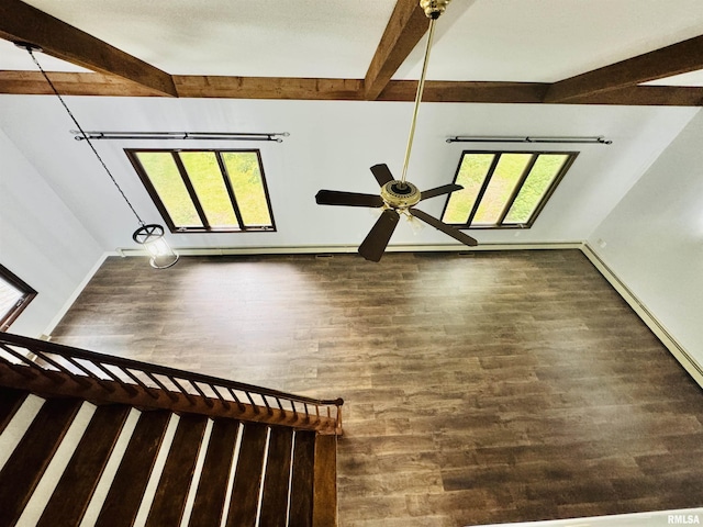 interior space with ceiling fan, baseboards, beam ceiling, and wood finished floors