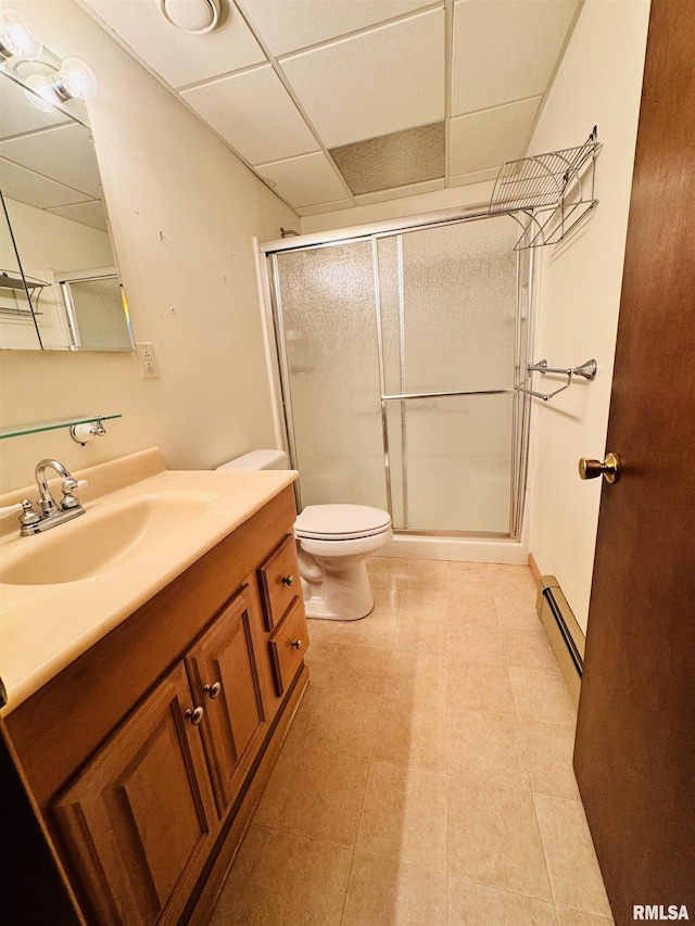 bathroom featuring toilet, a drop ceiling, a shower stall, baseboard heating, and vanity