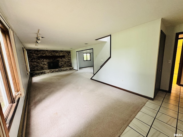 unfurnished living room featuring light colored carpet, a brick fireplace, and brick wall