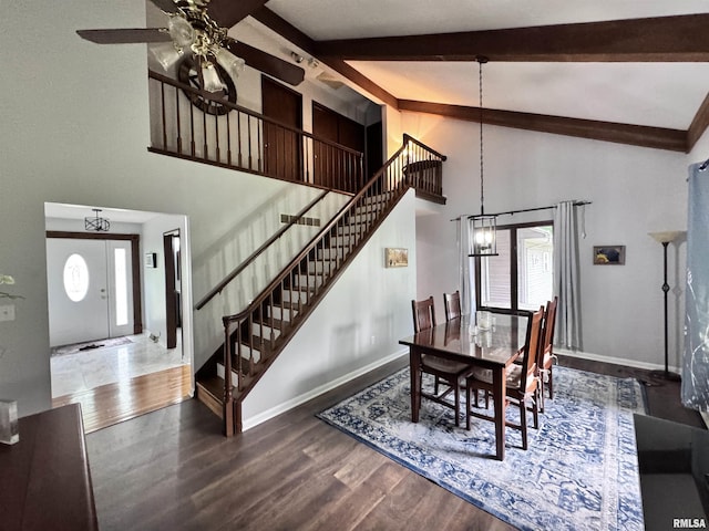 dining room featuring beamed ceiling, baseboards, wood finished floors, and stairs