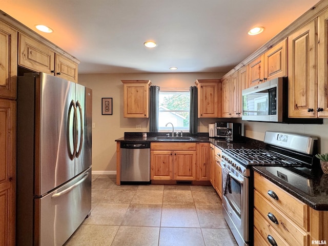 kitchen featuring sink, appliances with stainless steel finishes, light tile patterned floors, and dark stone countertops