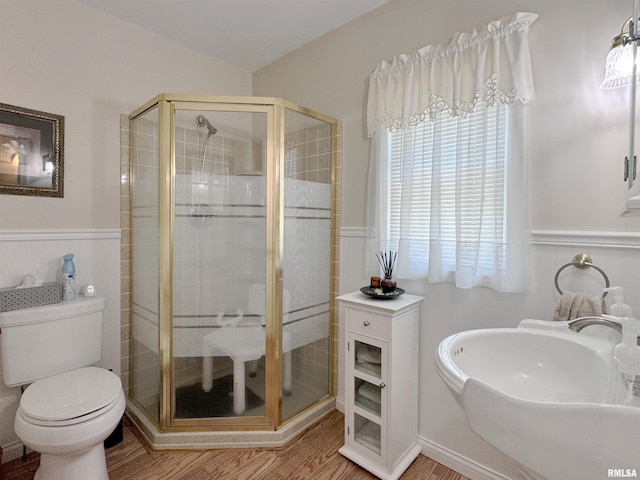 bathroom featuring sink, a shower with shower door, hardwood / wood-style flooring, and toilet